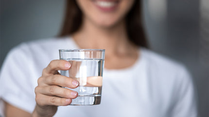 Muskeln: Frau zeigt ein Glas mit Wasser