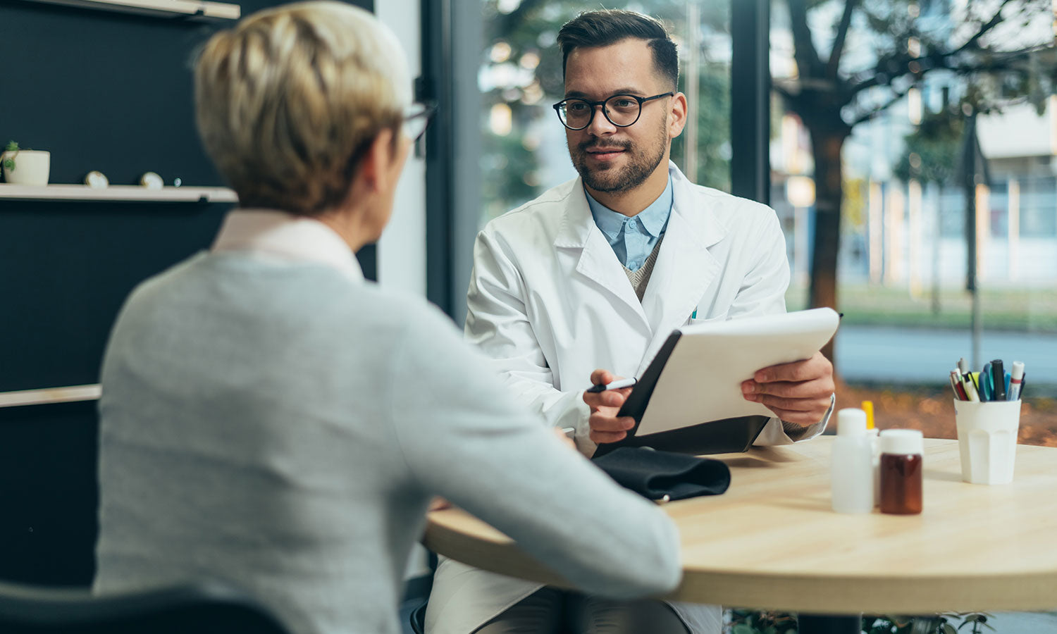 Ein Arzt berät eine Patientin und hält während des Gesprächs ein Klemmbrett