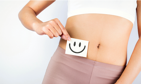 Was ist Kollagen: Frau hält Zettel mit Smiley vor ihren Bauch