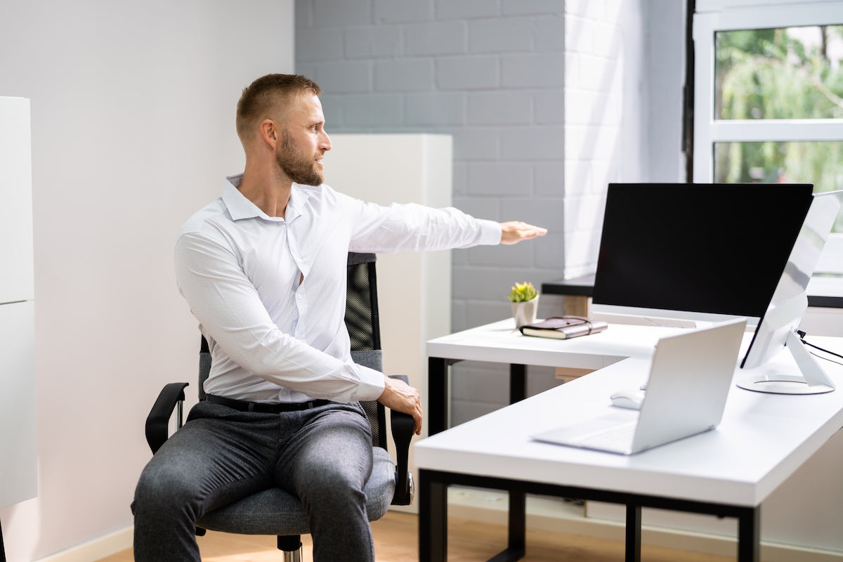 Mann macht eine Dehnübung im Büro