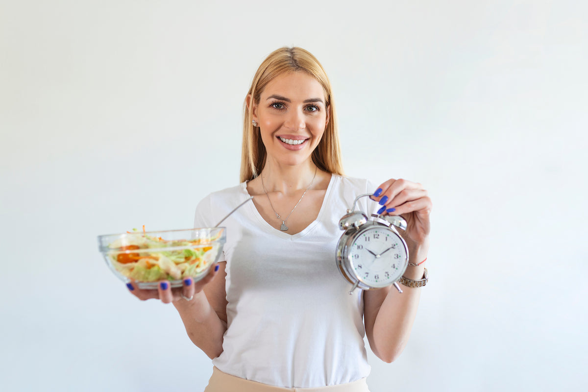 Frau hält Schüssel mit Essen und einen Wecker in den Händen