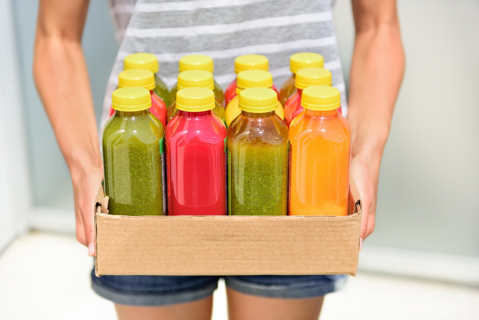 Ein Mann hält in einem Karton viele verschiedene Fruchtsäfte und Smoothies