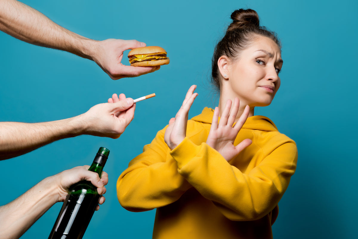 Frau sagt Nein zu einem burger, einer Zigarette und einer Flasche Alkohol