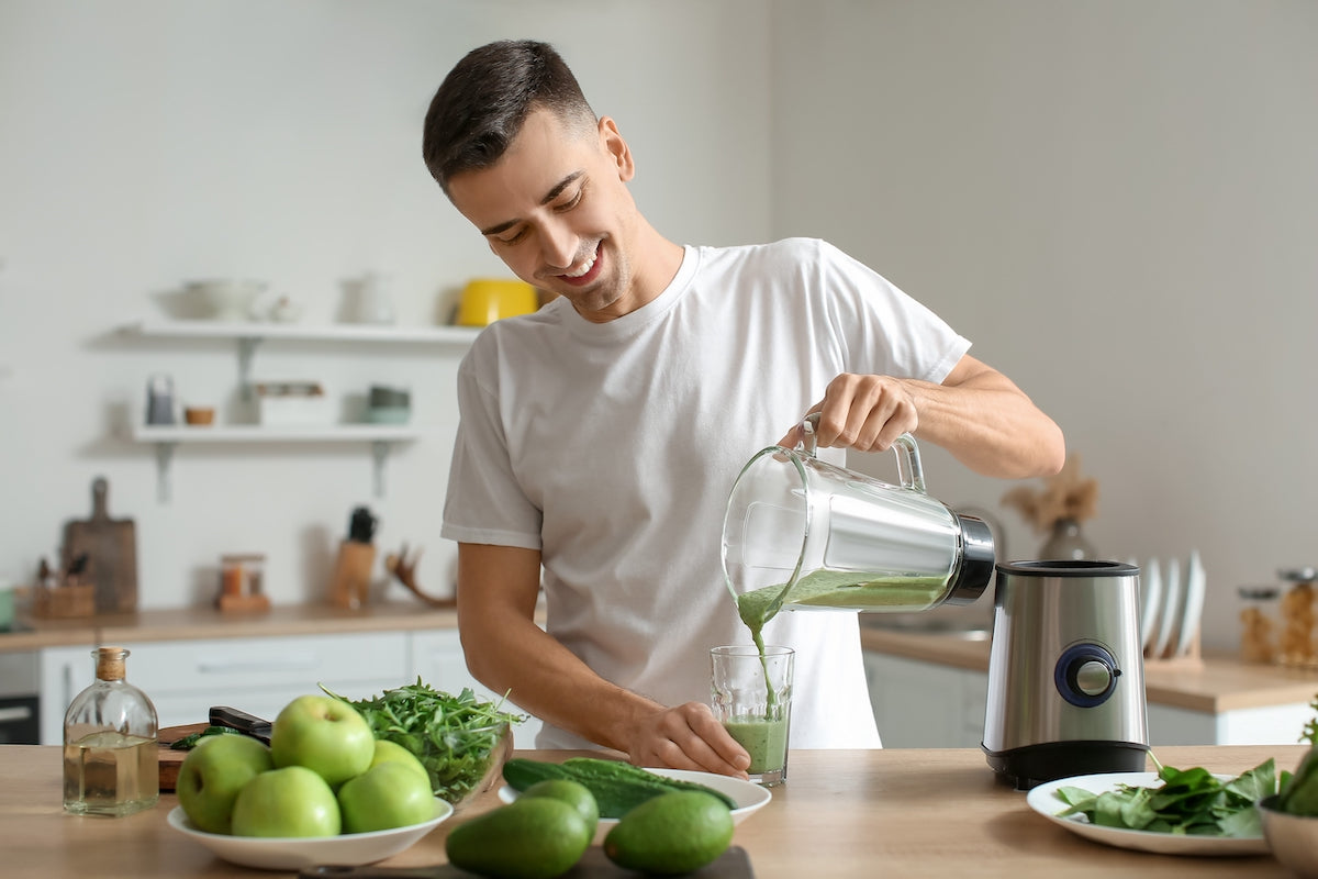 Mann macht sich Saft aus grünem Obst und Gemüse