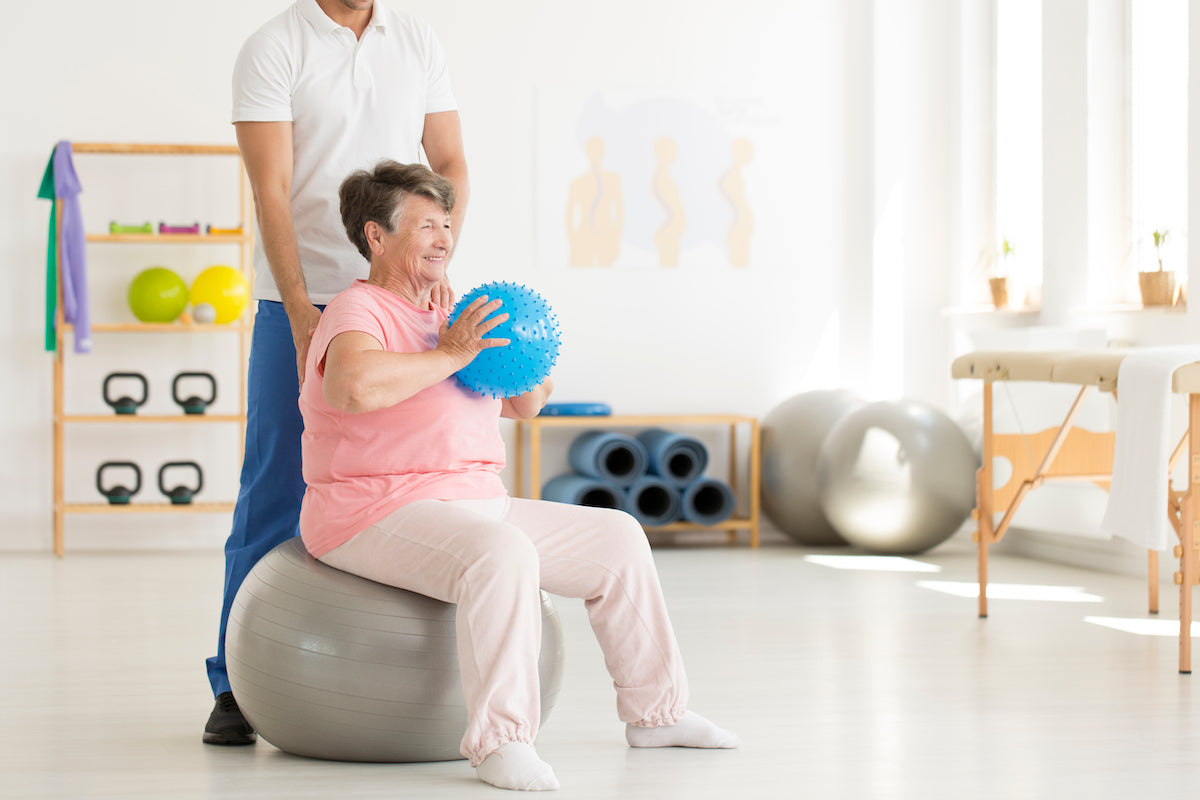 Die richtige Ernährung bei Arthrose: Ältere Frau macht Gymnastikübungen auf einem Gummiball