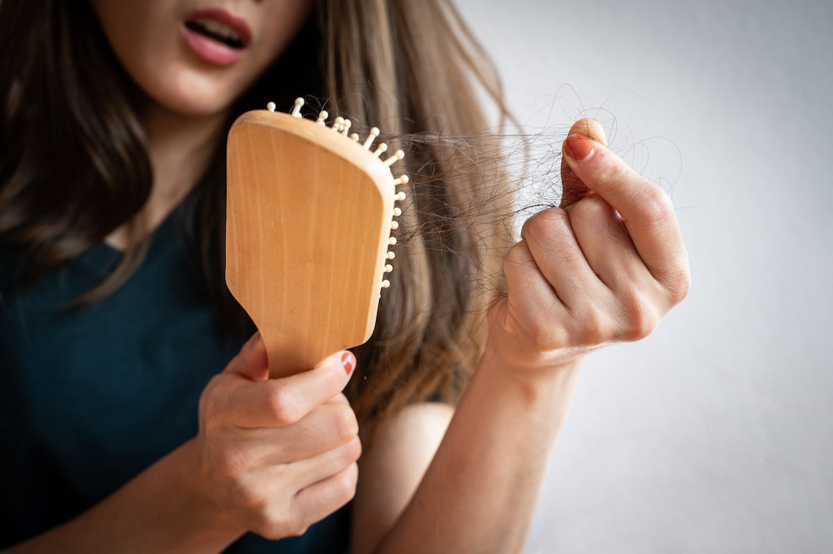 Frau hält Haarbürste mit vielen Haaren