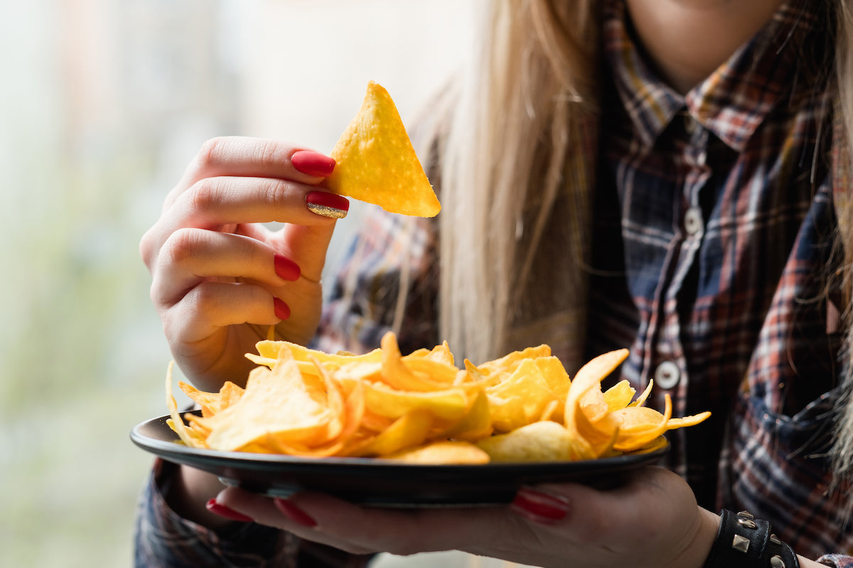 Frau isst Chips von einem Teller