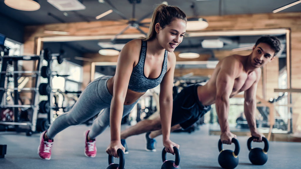 Eine Frau und ein Mann machen Kraftsport mit Kettlebells