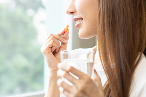 Vitamin-D-Wirkung: Frau nimmt eine Kapsel mit einem Glas Wasser ein