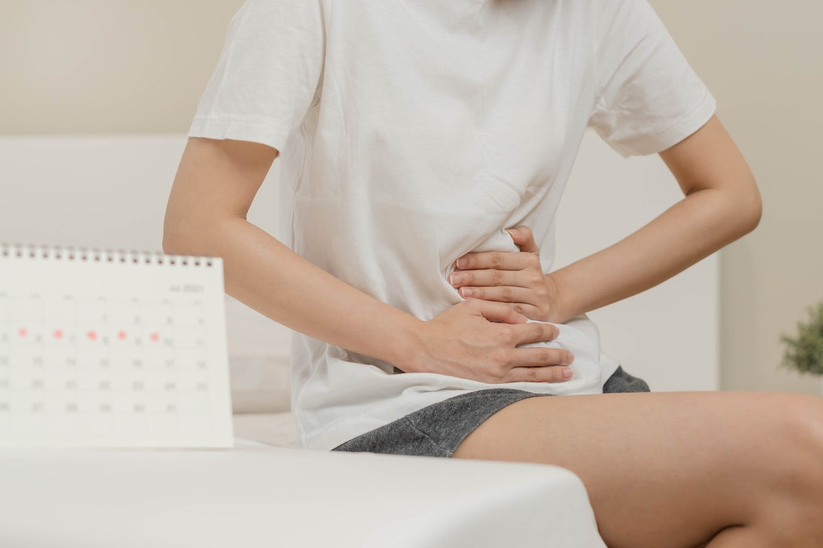 Eine Junge Frau hält sich den schmerzenden Unterleib aufgrund von Menstruationsbeschwerden