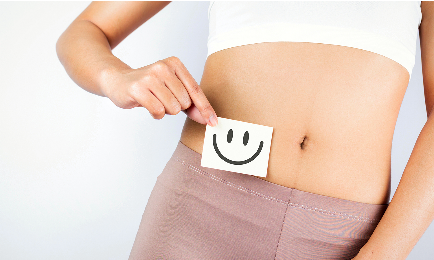 Frau hält Zettel mit Smiley neben ihren Bauch