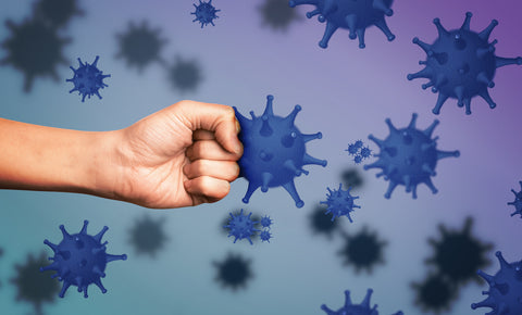 Eine Faust boxt gegen eine vergrößertes Modell eines Virus