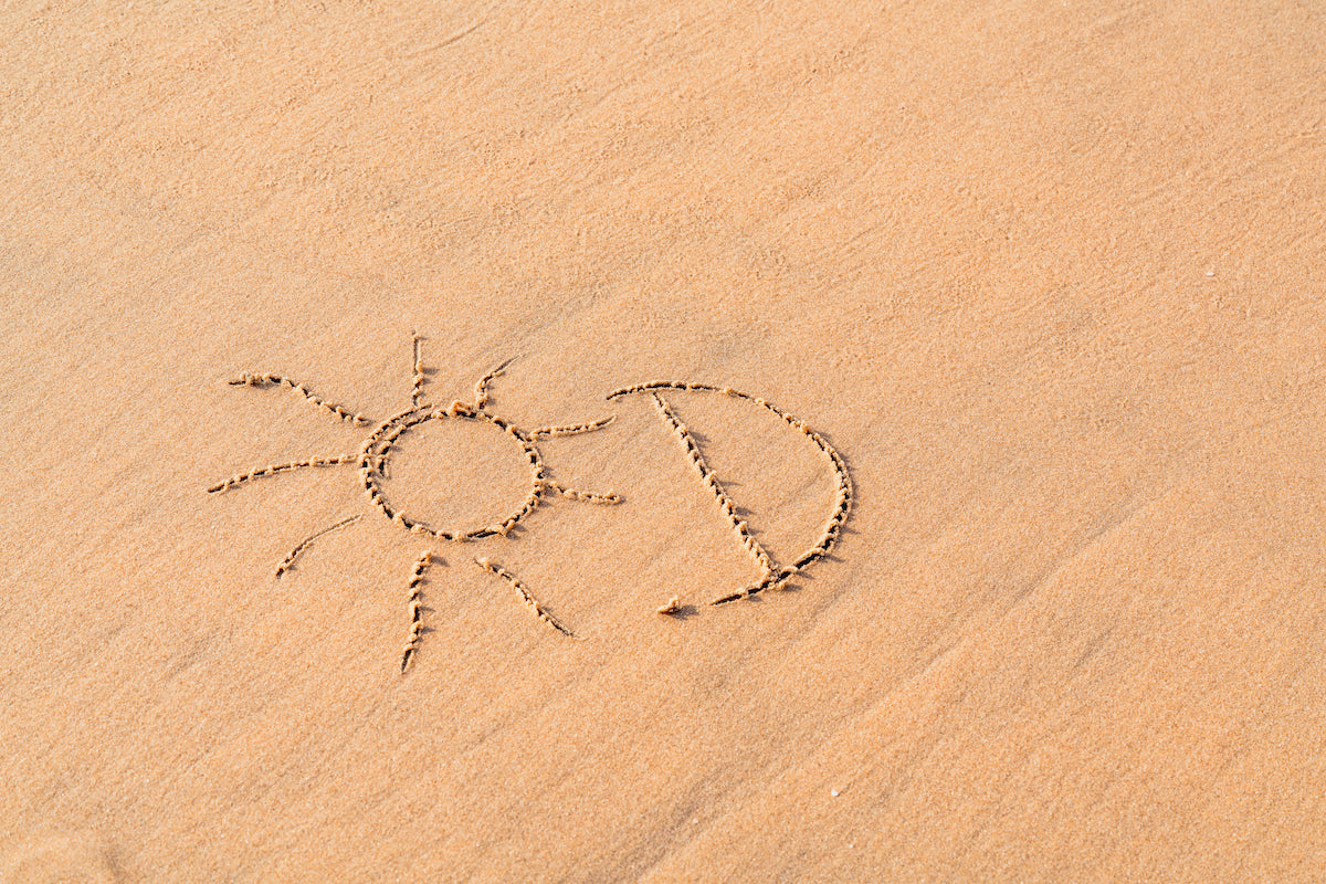 Eine am Strand in den Sand gemalte Sonne
