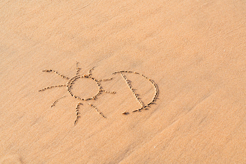 Eine am Strand in den Sand gemalte Sonne