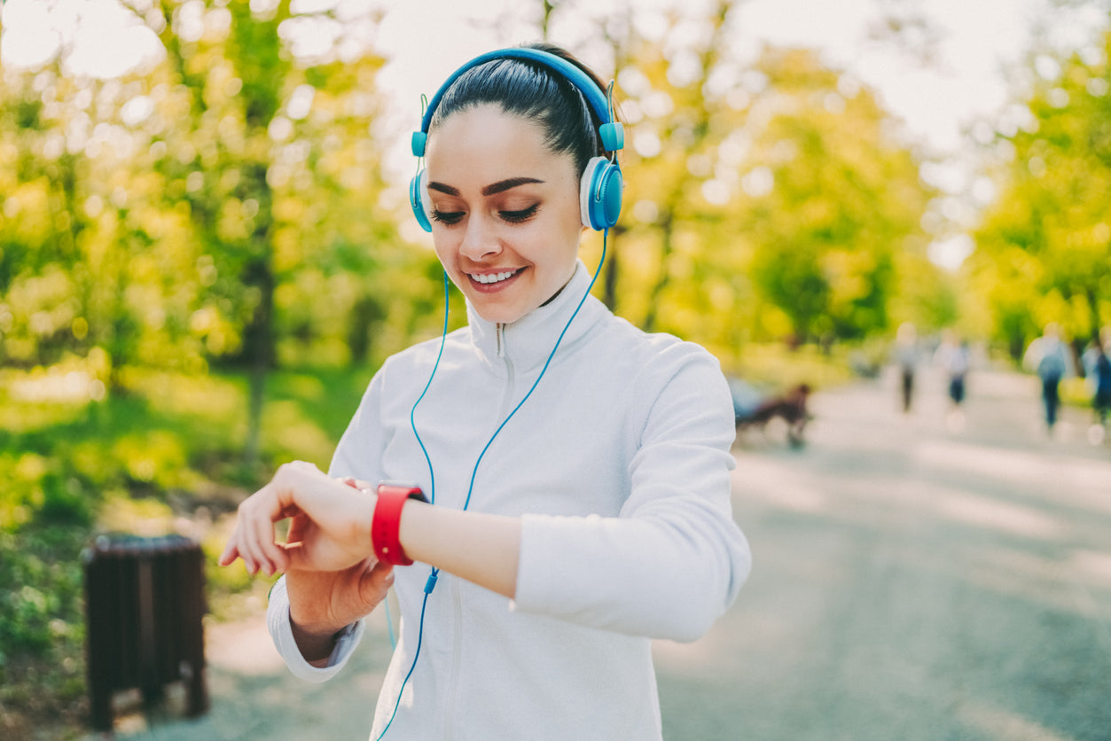 Fitness-Tracker Gesundheit: Frau schaut beim Joggen auf ihre Fitnessuhr