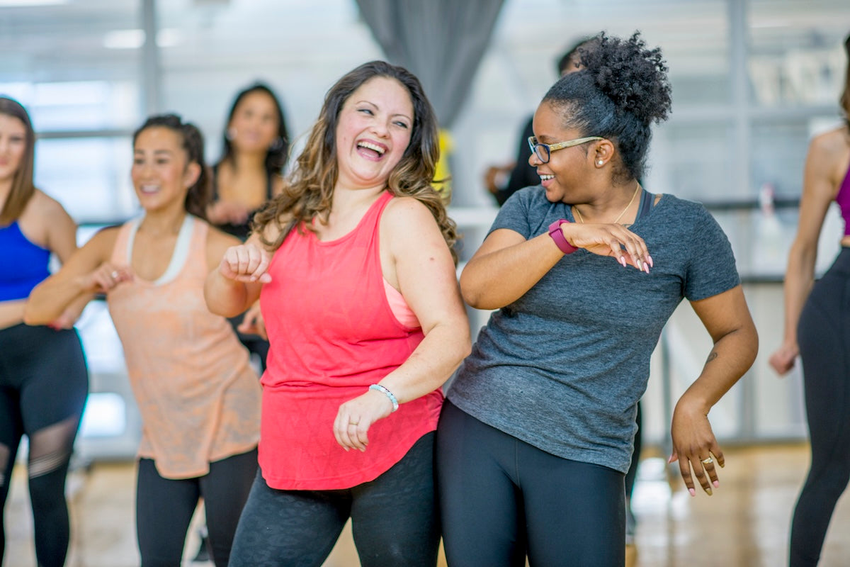 Abnehmen in den Wechseljahren: Zwei Frauen haben zusammen Spaß beim Fitnesstraining