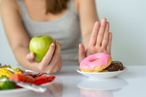 Frau isst lieber Apfel statt Donuts