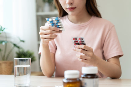 FAQ Multi-Komplex: Frau schaut sich zwei Blister mit Tabletten an